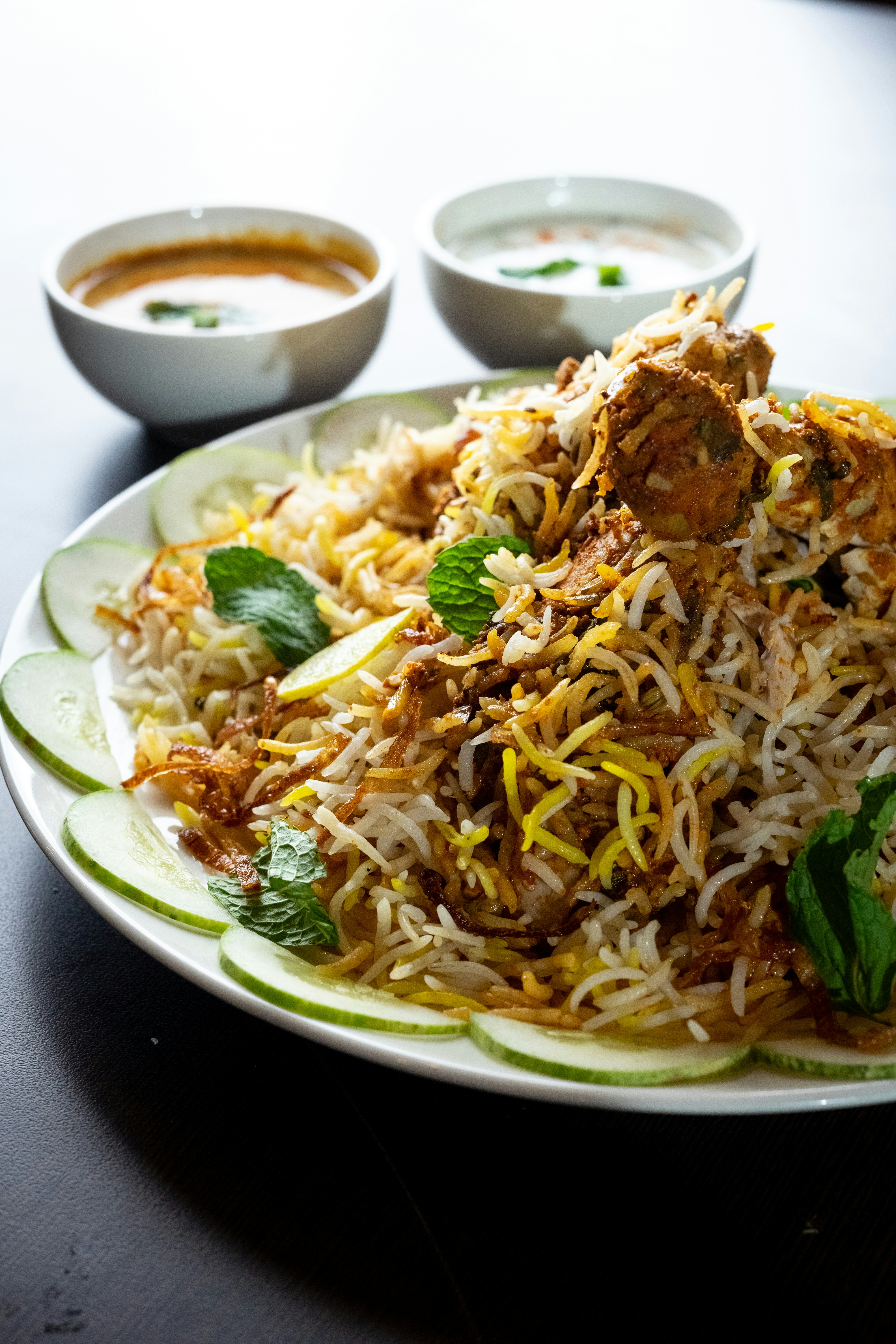 Hyderabadi biryani with saffron rice, mint and raita served on a white plate