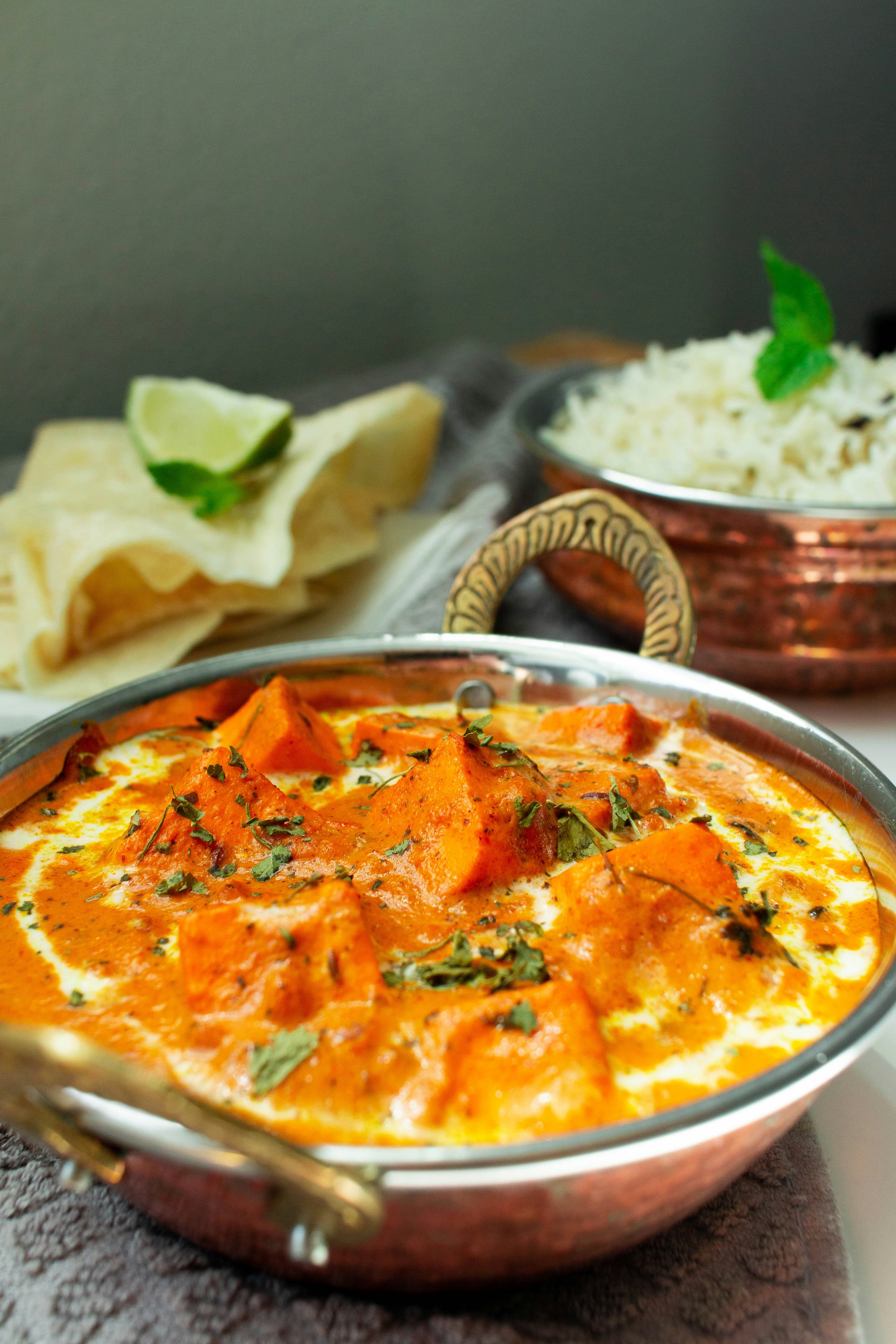Paneer curry in a copper karahi bowl with naan and rice